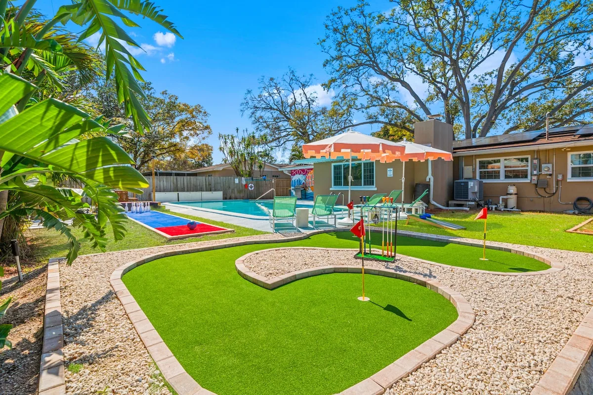 STR Cribs beach rental backyard with pool, mini golf, lawn games, and fenced activity zones