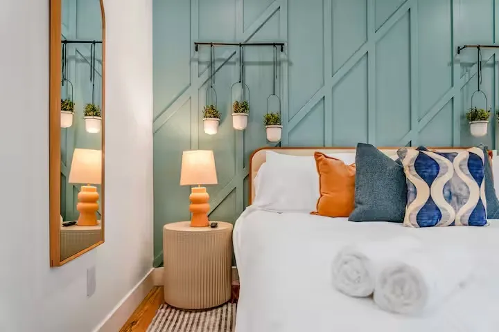 Modern bedroom corner with a bed featuring colorful pillows.