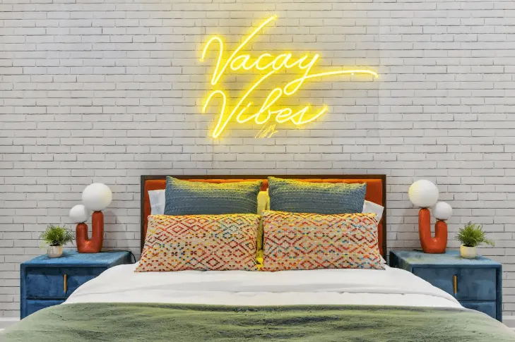Modern bedroom with a bed featuring patterned pillows, green blanket